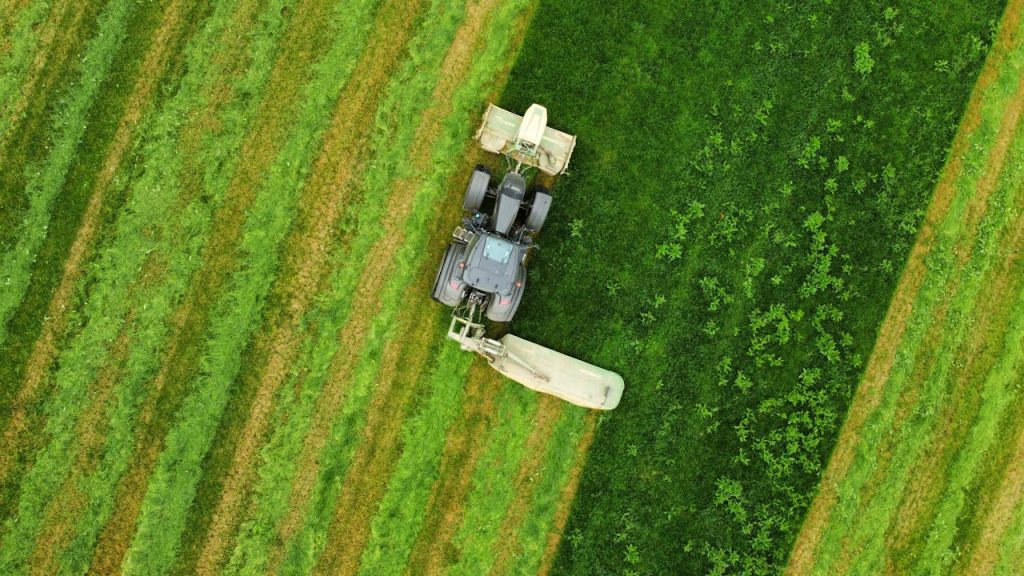 Mastering the First Impression: Your intriguing post title goes here Aerial shot of a tractor cutting through vibrant green farmland, showcasing agriculture at work.